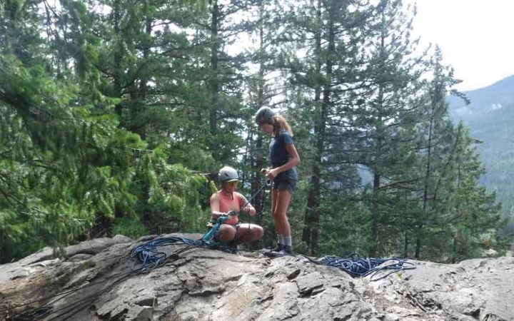 an outward bound instructor gives direction to a student preparing to rock climb